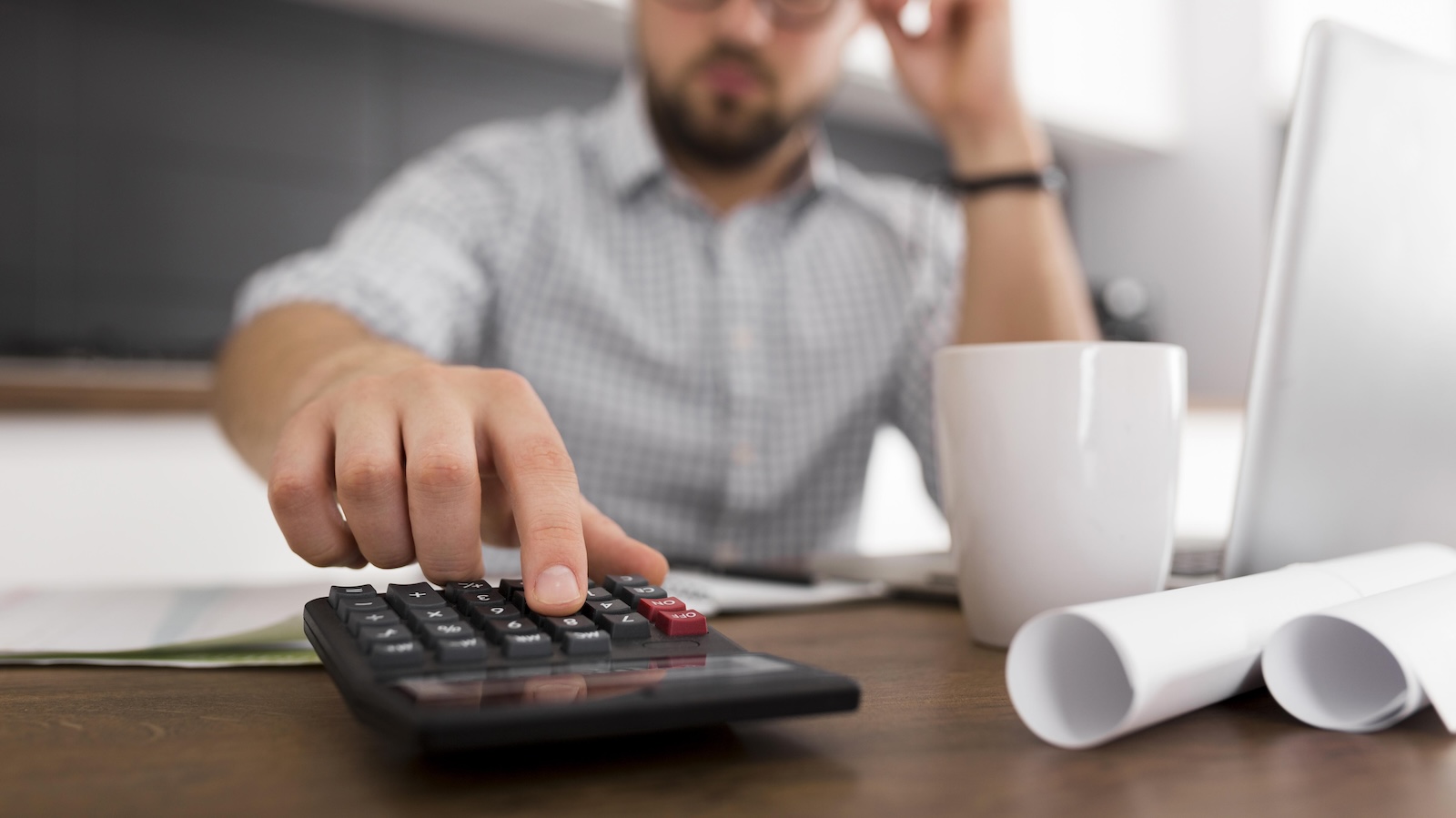 Homem usa calculadora na mesa do escritório para calcular redução de custos da empresa