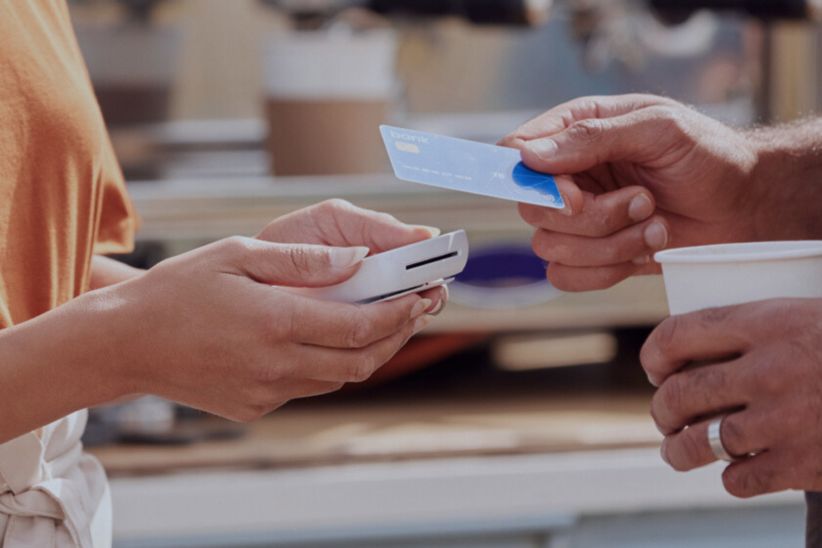 Atendente de cafeteria recebendo pagamento na maquininha de cartão de crédito