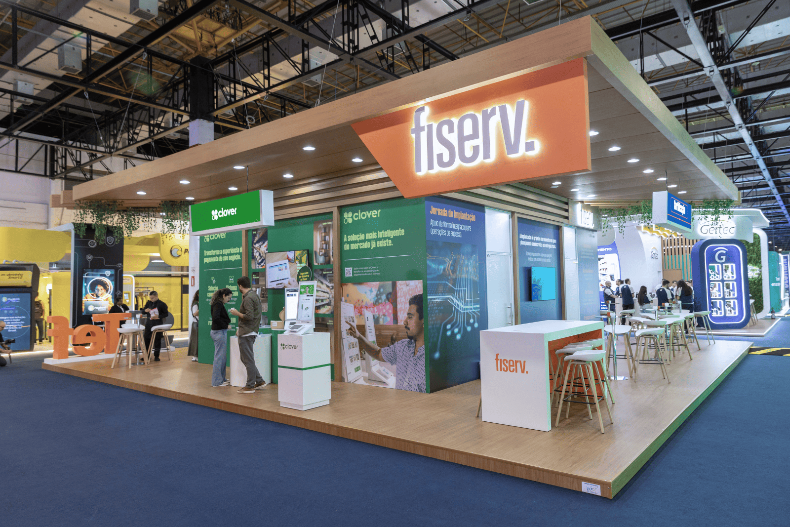 Stand da Fiserv, com painéis de produtos e espaços para networking, na feira Autocom 2026